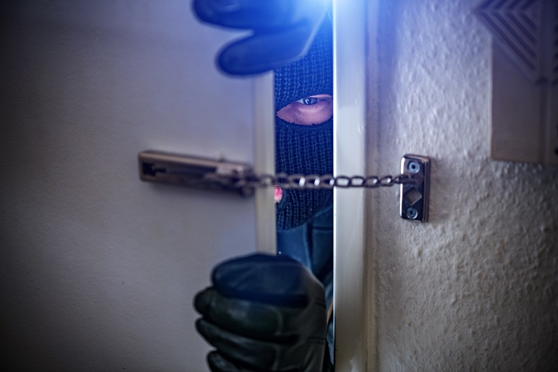 Maskierter Einbrecher in einer Haustüre