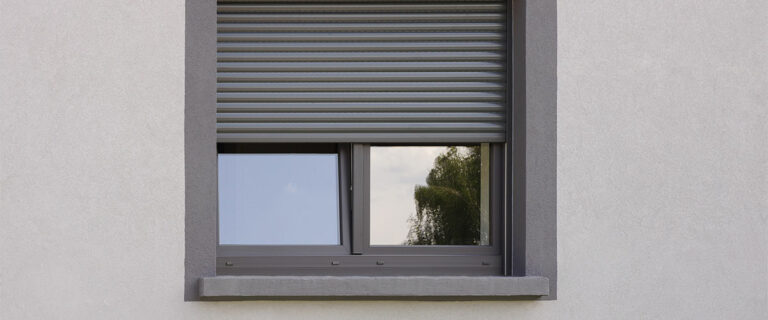 Dunkles Kunststofffenster mit Rollladen in grauer Fassade
